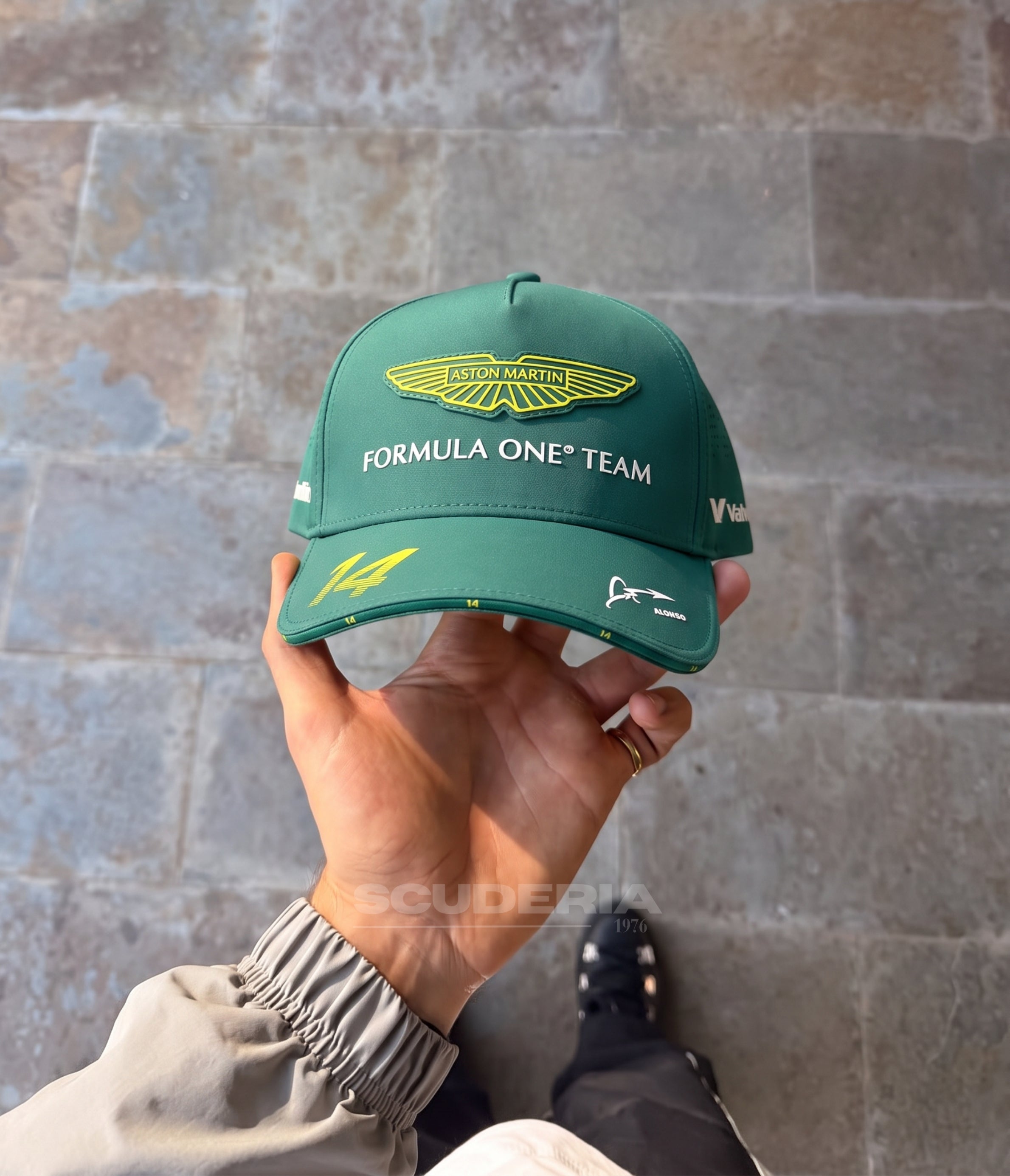 Hand holding the green Aston Martin F1 Alonso 2025 cap showing the No.14 on the brim