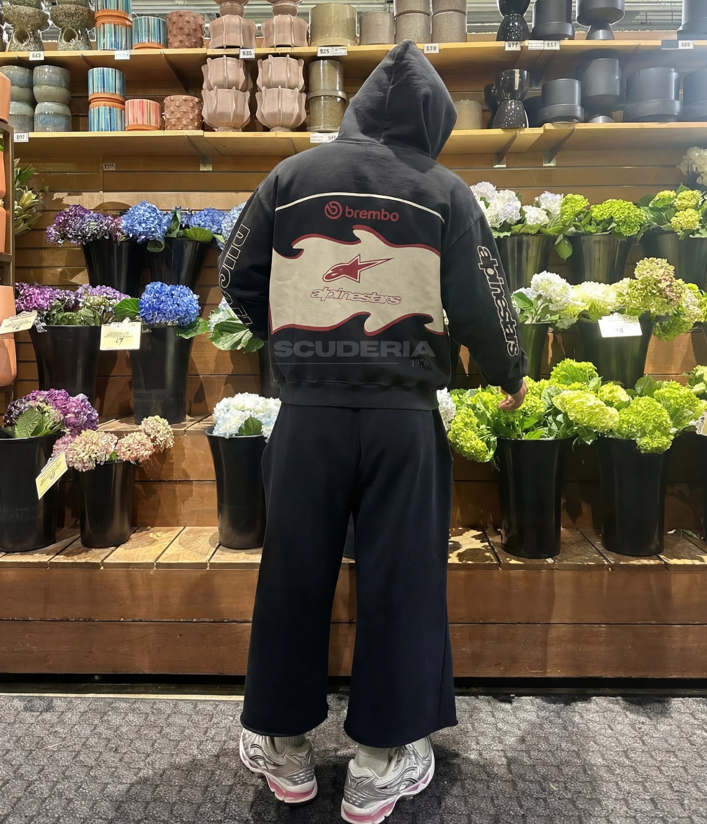 Ducati Alpinestars Racing Hoodie black washed lifestyle back view women – vintage oversized motorsport hoodie with Alpinestars and Brembo back panel styled with wide-leg pants in a flower shop