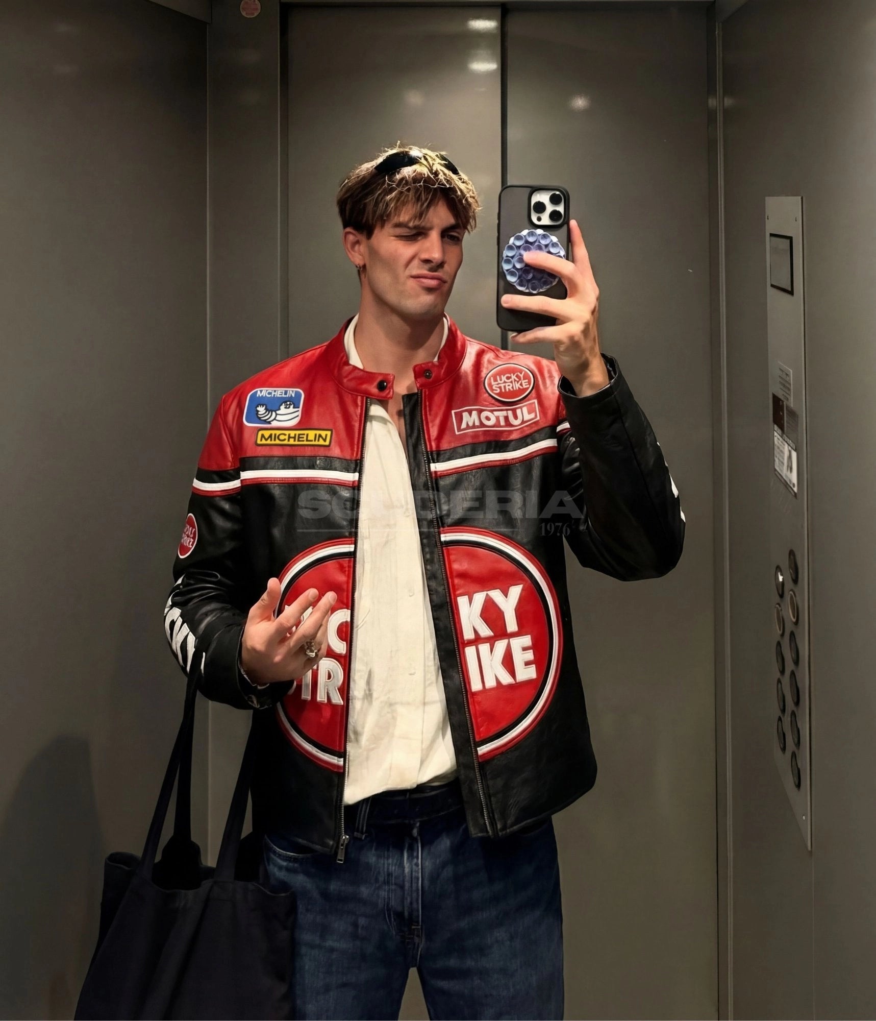 Lucky Strike Leather Jacket Red Edition mirror selfie lifestyle men – vintage moto leather jacket with Lucky Strike circle logo, Michelin and Motul patches, red and black color block, elevator mirror setting