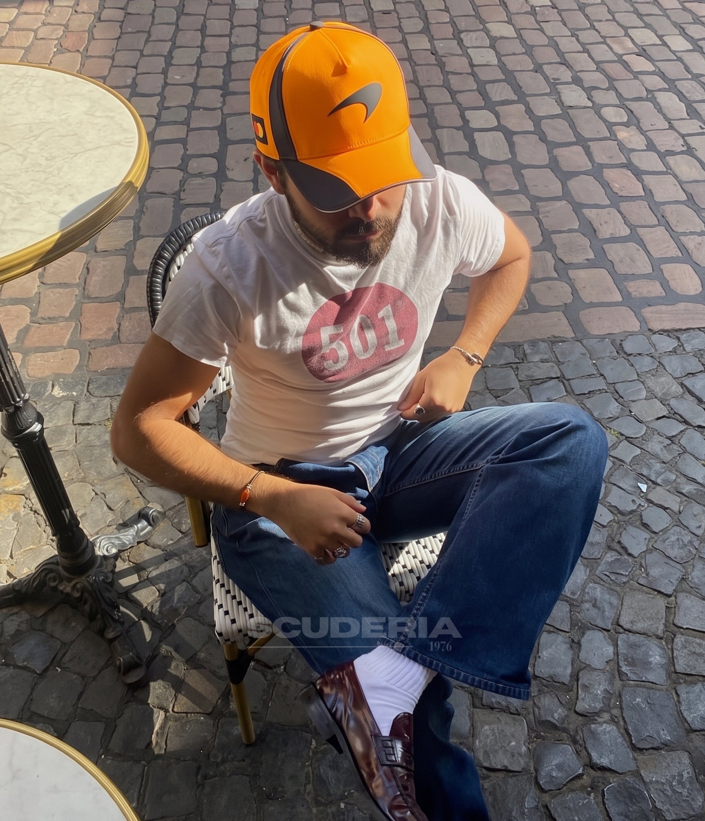 Man wearing the McLaren F1 2025 papaya cap at a cafe terrace