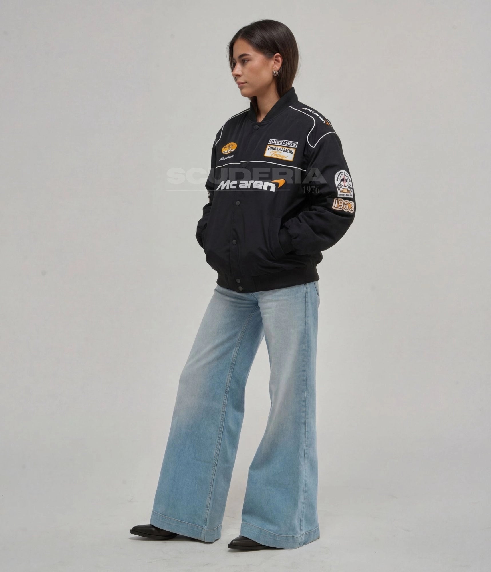 McLaren F1 Racing Jacket black side view women – vintage racing bomber with embroidered McLaren logo, Formula 1 Racing Team and 1963 sleeve patches, white piping detail, styled with wide-leg flare jeans
