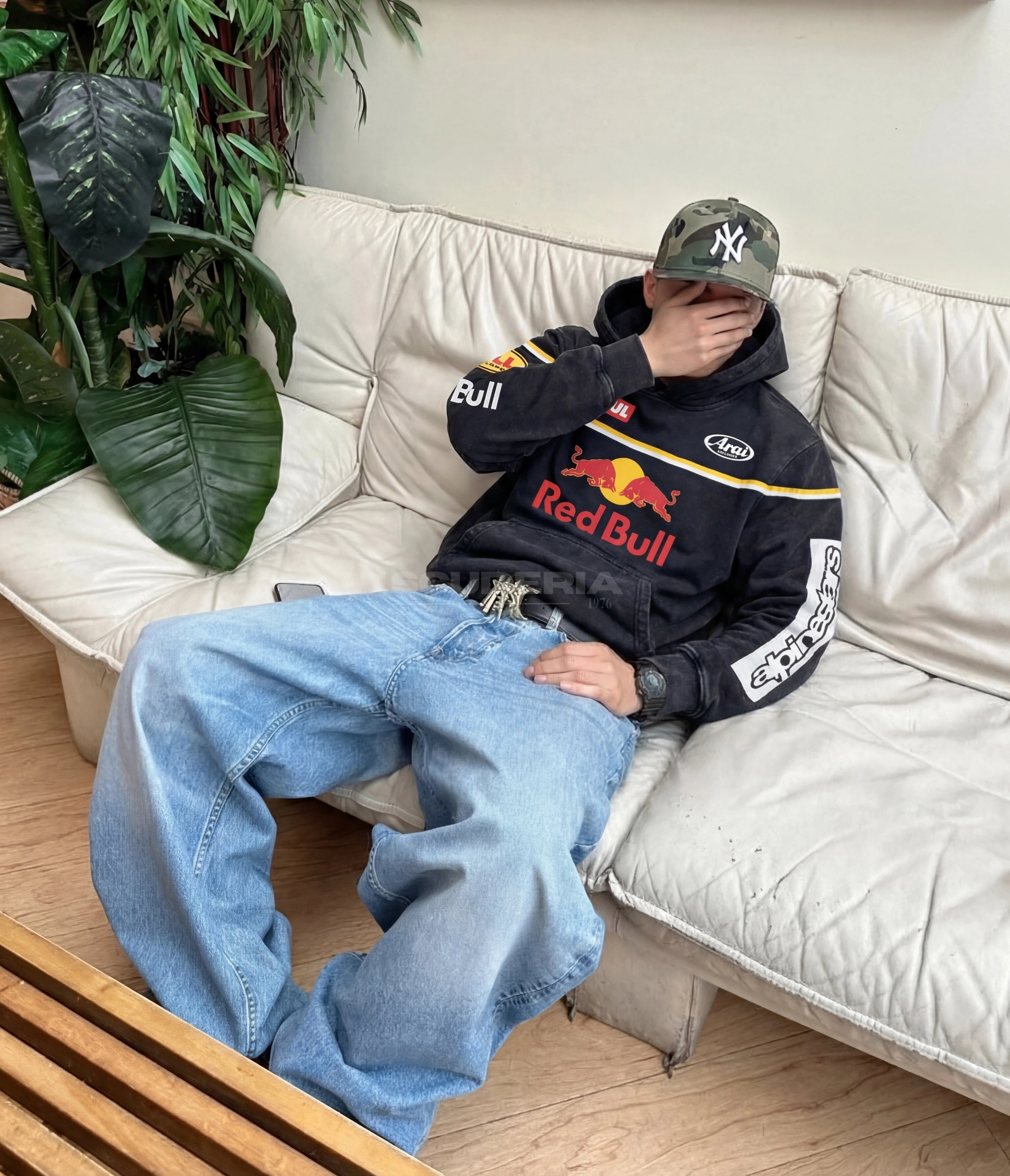 Red Bull Racing Hoodie black washed lifestyle man – vintage oversized motorsport sweatshirt with Red Bull chest logo styled relaxed on sofa with baggy jeans and camo cap