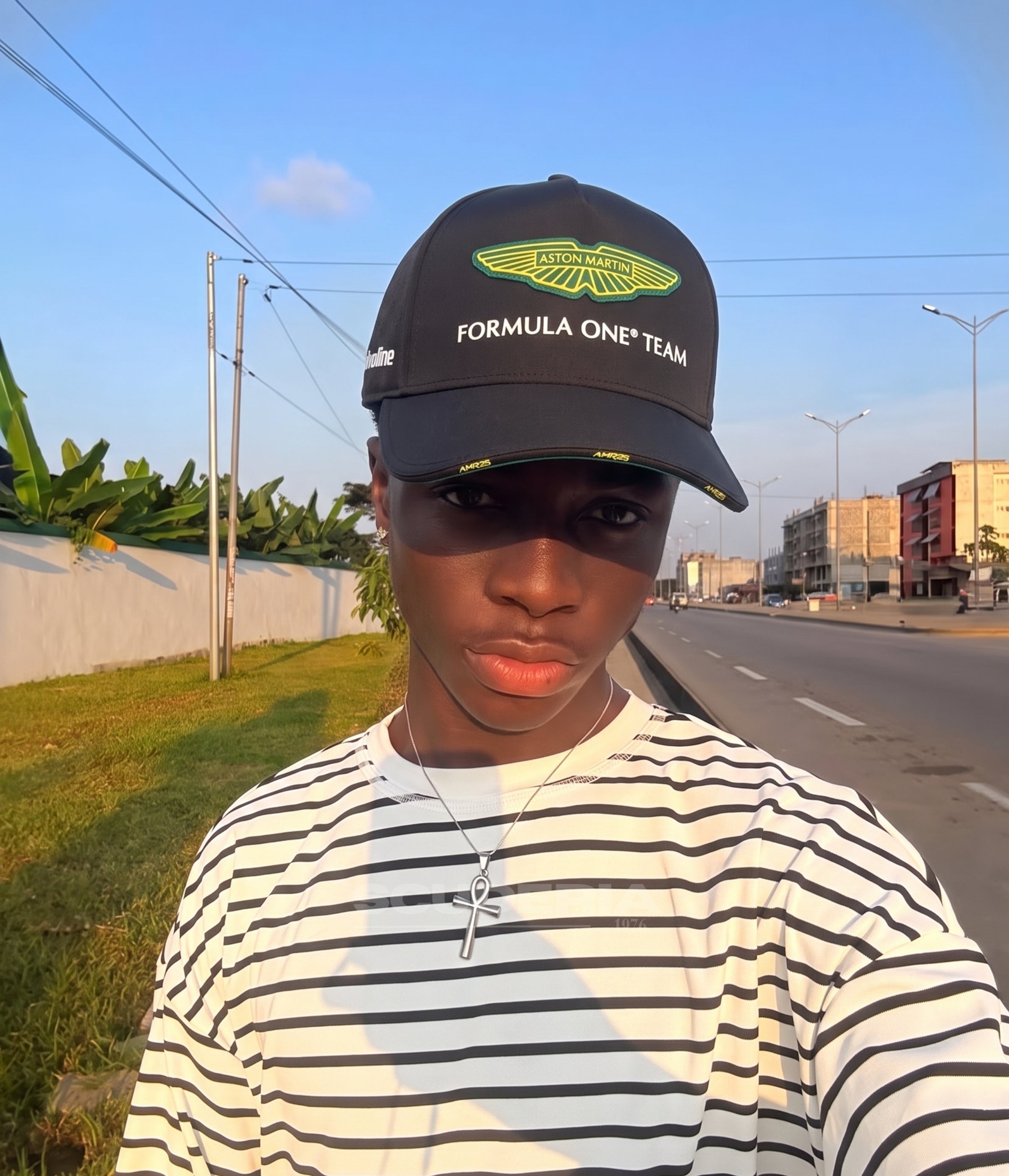 Man wearing the black Aston Martin F1 2025 cap by the roadside