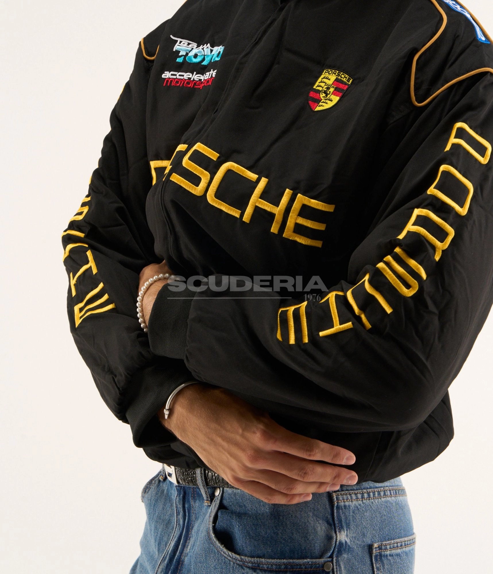 Porsche Vintage Racing Jacket black gold front detail men – vintage padded bomber showing gold embroidered Porsche chest logo, Porsche crest patch, Team Toyo Accelerate Motorsport embroidery and gold piping
