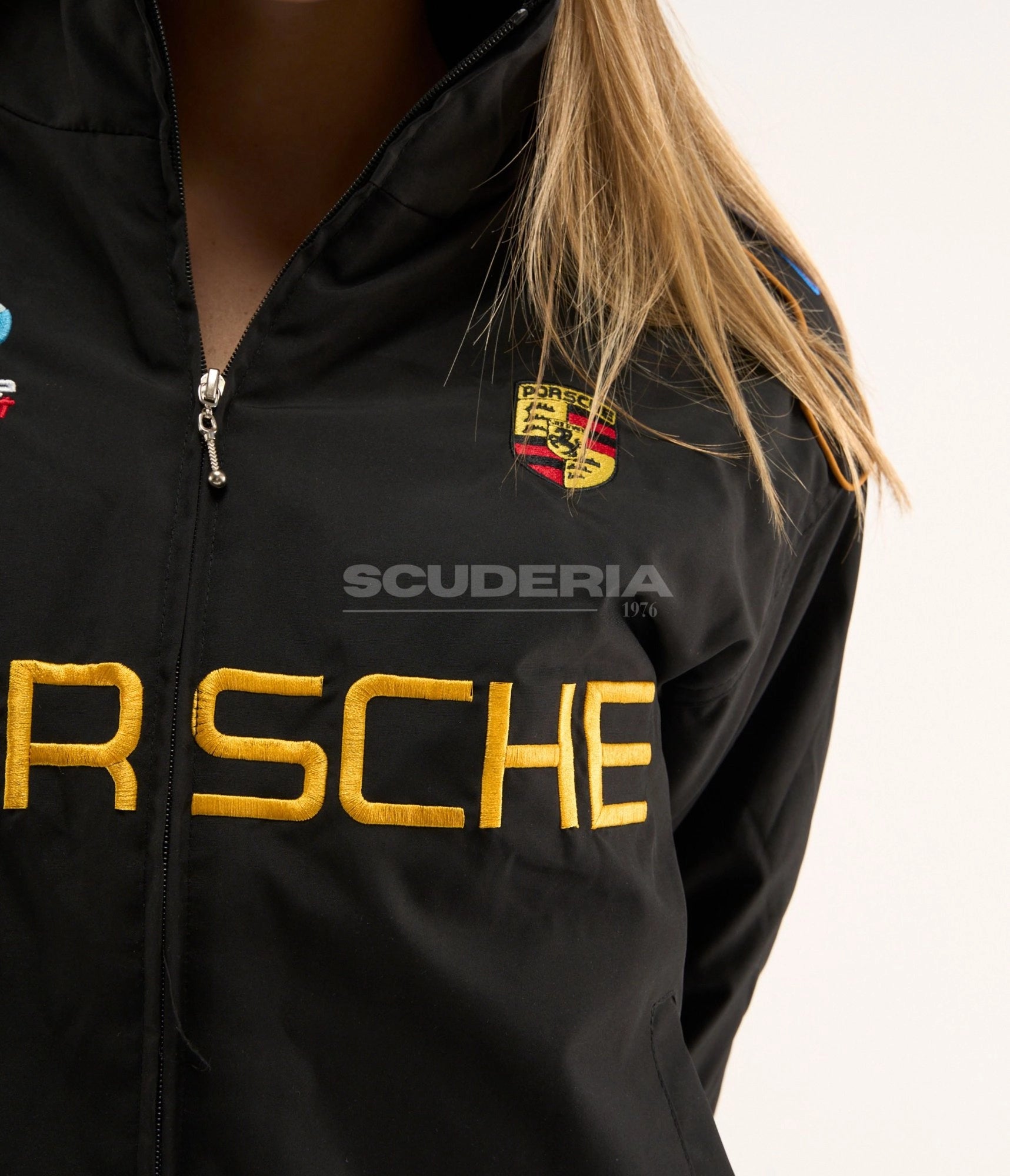 Porsche Vintage Racing Jacket black gold front detail women – vintage padded bomber showing gold embroidered Porsche crest patch and chest logo close-up, gold piping trim detail