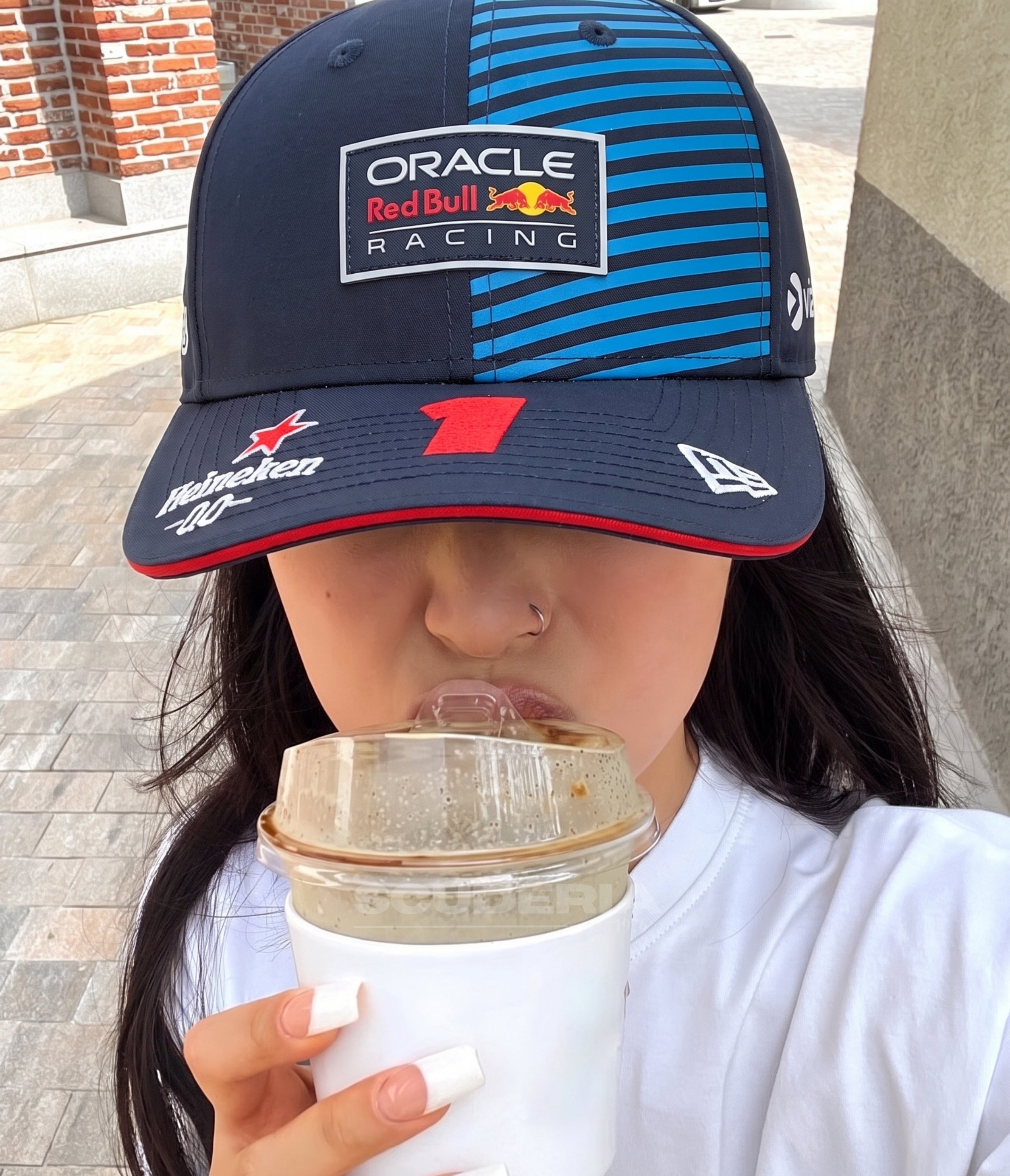 Woman wearing the Red Bull F1 Verstappen 2024 cap with an iced coffee